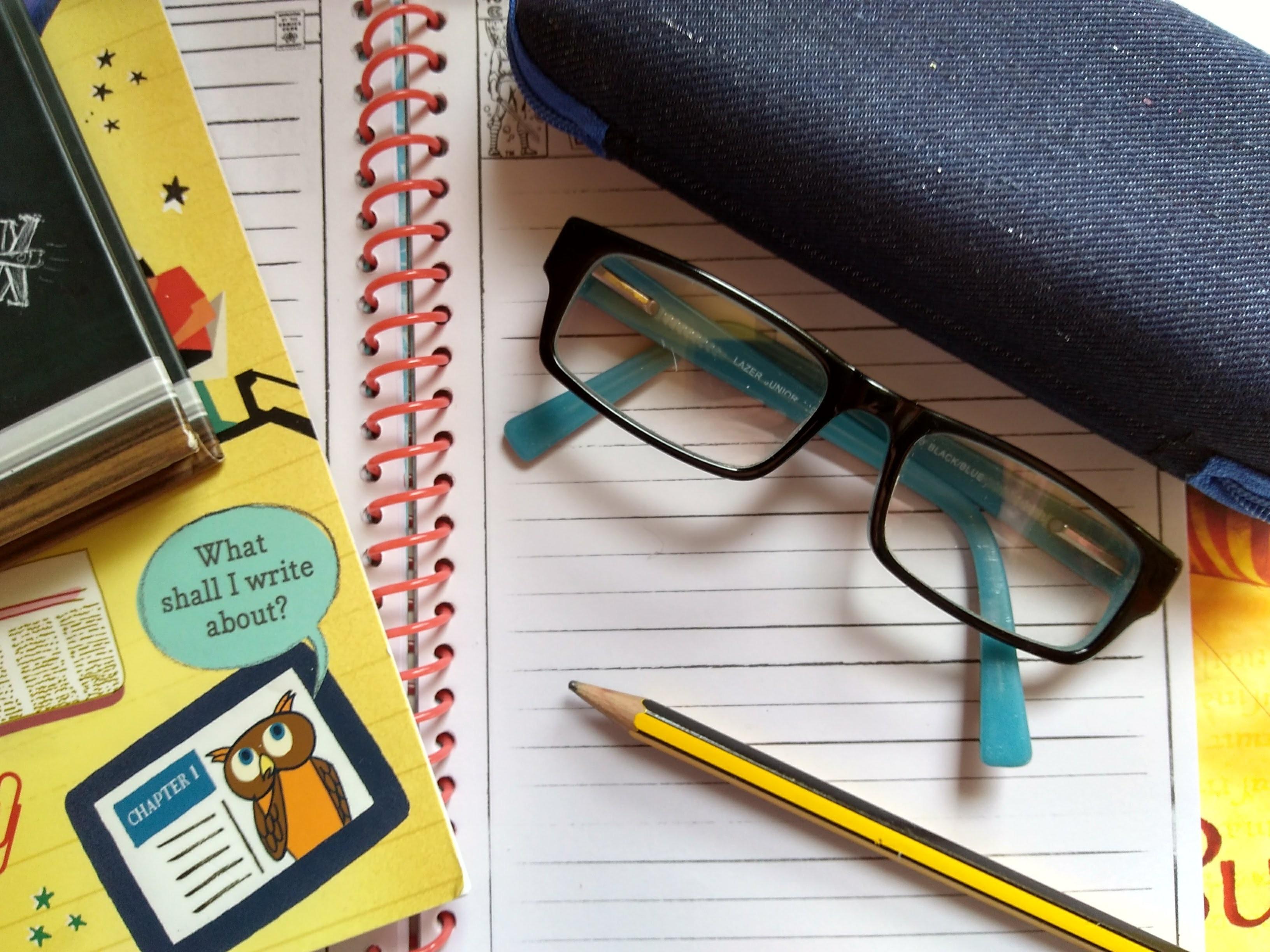 childrens-glasses-for-reading-resting-on-notebook-with-pencil-books-to-side